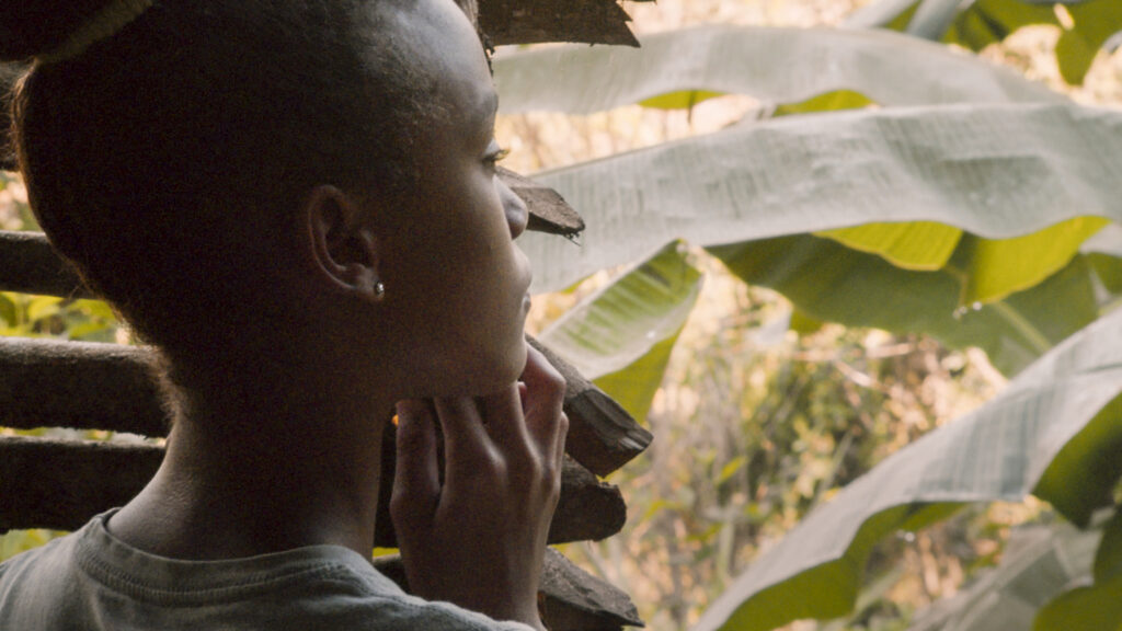 - Groovevolt Person in profile resting chin on hands, outdoors among large green banana leaves in the background.
